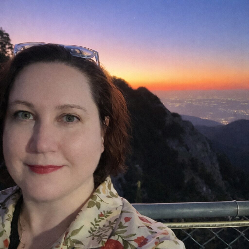 Clinical Psychologist, Jenny MacQuarrie, at twilight in front of mountains and the ocean view.