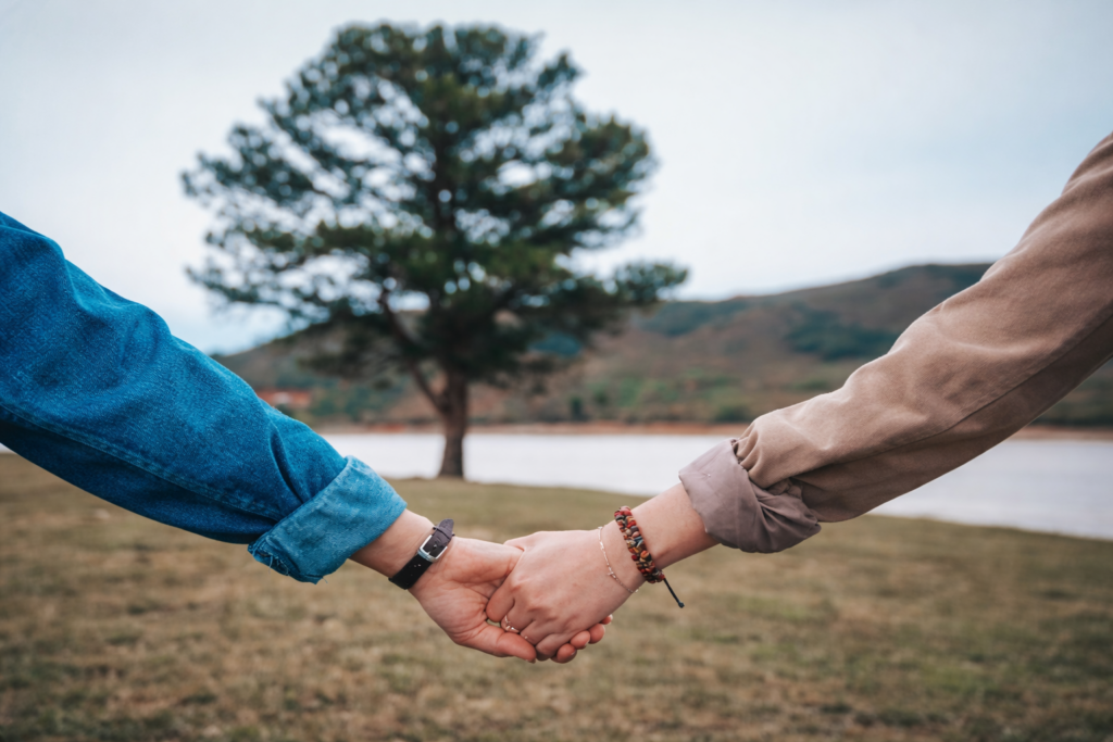A couple with arms out stretched holding hands walking in nature