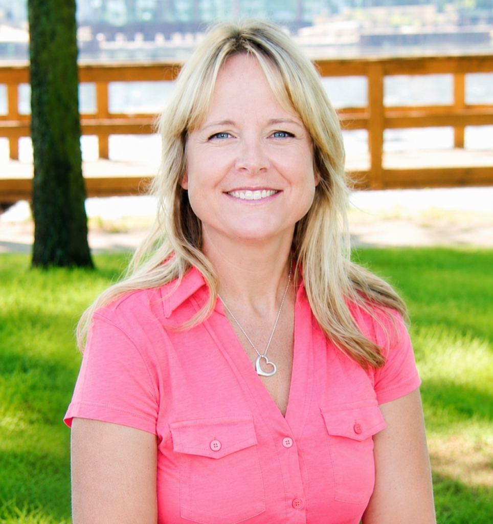 Michelle Trudell, LMSW, CAADC sitting in a park with a river behind her.